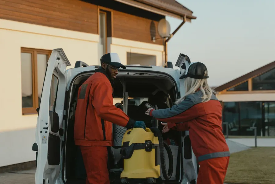 A commercial cleaning crew loading equipment into a service van