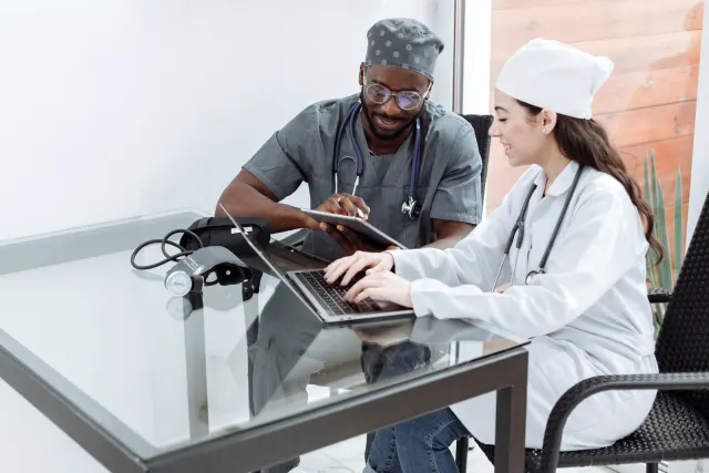 Two healthcare professionals reviewing information on a laptop and tablet